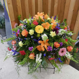 Large mixed floral spray with orange lilies, roses, and gerbera daisies