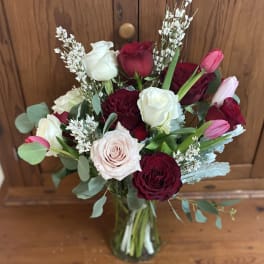 Bouquet of red, white, and pink roses in a glass vase