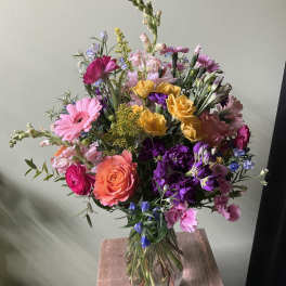 Mixed bouquet of pink, purple, yellow, and orange flowers in a glass vase