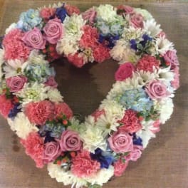 Heart-shaped floral wreath with pink, white, and blue flowers