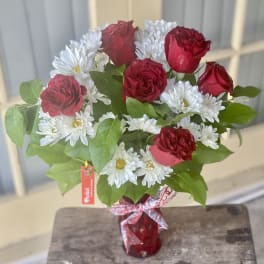 Bouquet of red roses and white daisies in a red vase
