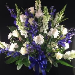 White and blue floral standing arrangement with a blue ribbon bow