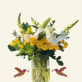 Yellow roses and white lilies in a clear glass vase