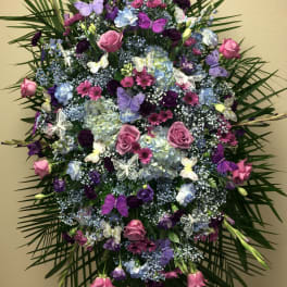 Large standing floral spray with pink and purple flowers and butterfly accents