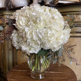 White hydrangea bouquet in a clear glass vase with eucalyptus accents