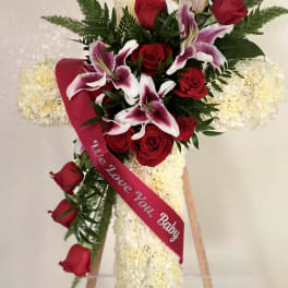 Standing floral cross with red roses and white lilies on an easel