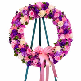 Circular floral wreath on an easel with pink, purple, and white flowers