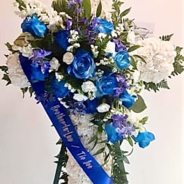 Blue and white funeral spray with roses and hydrangeas on a stand