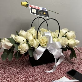 White rose arrangement in a black basket with a white ribbon and card pick