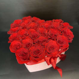 Heart-shaped box filled with red roses and a red ribbon
