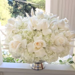 White roses and hydrangeas arranged in a silver vase