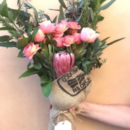 Pink and white bouquet with a large protea in burlap wrap
