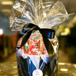 Gift basket with assorted candy wrapped in clear cellophane and a black ribbon