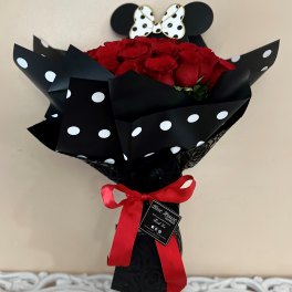 Bouquet of red roses wrapped in black polka-dot paper with a red ribbon