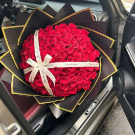 Large bouquet of red roses wrapped in black paper with gold trim