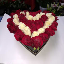 Heart-shaped arrangement of red and white roses in a black box