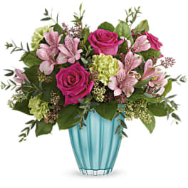 Pink roses and lilies arranged in a blue glass vase