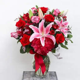 Bouquet of red and pink roses with lilies in a glass vase