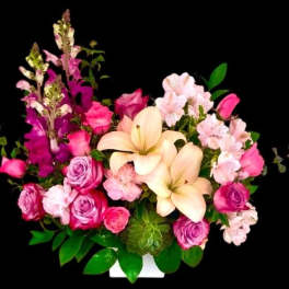 Pink and cream floral arrangement with roses, lilies, and alstroemeria in a white container