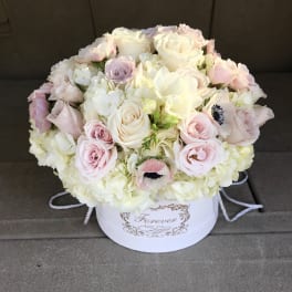Round bouquet of pale pink and white roses in a white hatbox