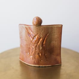 Small ceramic vessel with a textured copper-brown glaze and rounded top