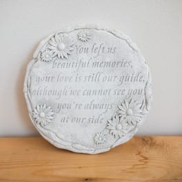 Round memorial plaque with daisy decorations and engraved text