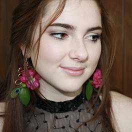 Woman wearing pink floral earrings and a black beaded top