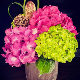 Pink and green hydrangea arrangement in a textured vase with decorative accents