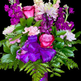 Bouquet of pink and purple flowers with a purple ribbon in a vase