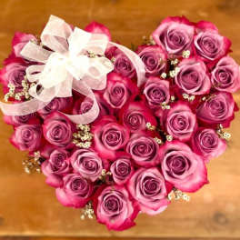 Heart-shaped bouquet of pink and purple roses with a white ribbon bow
