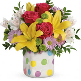 Bouquet of pink roses, yellow lilies, and daisies in a polka-dot vase
