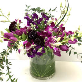 Purple tulips and orchids in a glass vase