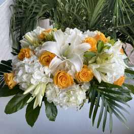 White lilies and yellow roses in a low floral arrangement