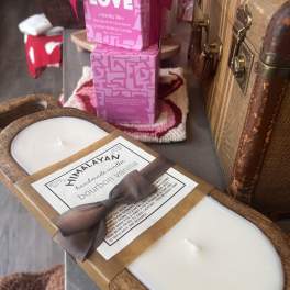 Assorted scented candles in decorative packaging and wooden trays