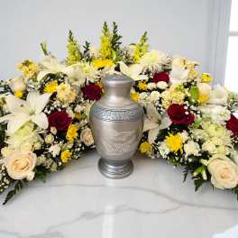 Symmetrical funeral floral arrangement with a silver urn in the center