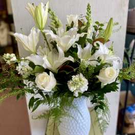 White lilies and roses arranged in a white vase