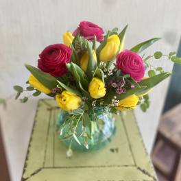 Bouquet of pink ranunculus and yellow tulips in a glass vase
