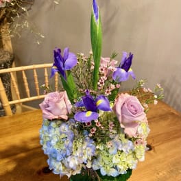 Bouquet of lavender roses, blue hydrangeas, and purple irises in a vase