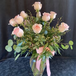Pink roses in a glass vase with a pink ribbon