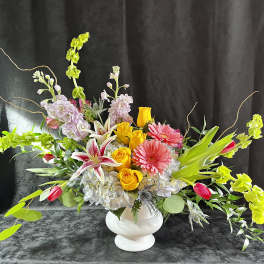 Colorful mixed flower arrangement in a white vase with long branching accents