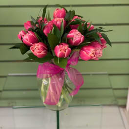 Pink tulip bouquet in a clear glass vase with a pink ribbon