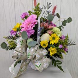 Mixed bouquet in a white container with a daisy-print bow