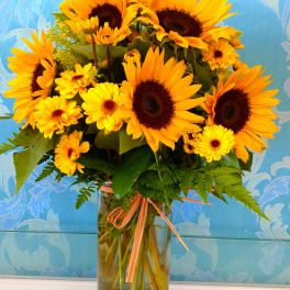 Sunflower and yellow daisy bouquet in a clear glass vase