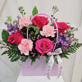 Pink roses and carnations in a lavender gift box with a ribbon handle