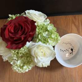 Bouquet of red and white roses with green hydrangeas beside a small white bowl