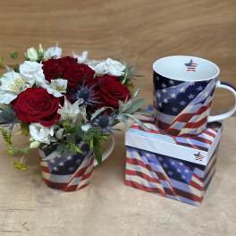 Red and white rose bouquet in a patriotic mug beside a matching mug and box