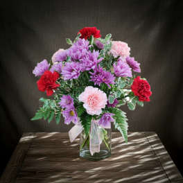 Bouquet of purple, pink, and red flowers in a clear glass vase