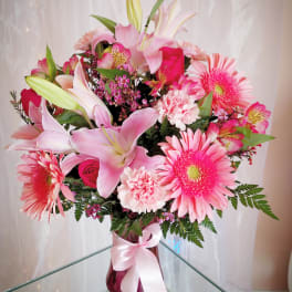 Pink and white mixed bouquet with lilies, gerbera daisies, and carnations in a glass vase