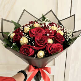 Bouquet of red roses with gold-wrapped chocolates and baby's breath