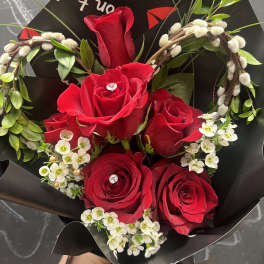 Bouquet of red roses with white filler flowers in black wrapping